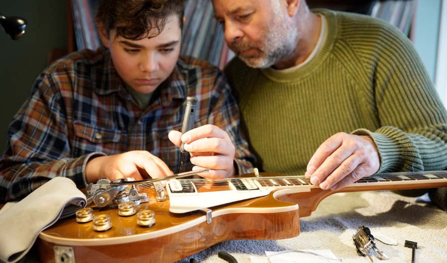 תמונה של אבא ובנו מתקנים גיטרה