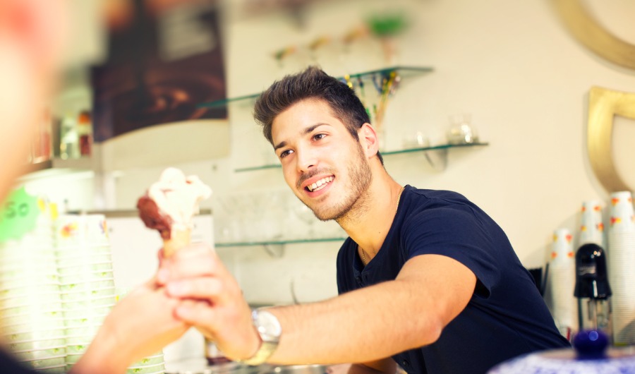 תמונה של בחור מגיש גלידה בגביע ללקוח