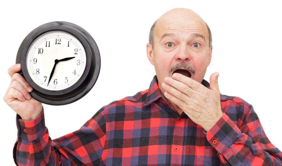 אדם עומד עם פרצוף משתהה מחזיק בידו שעון אנלוגי